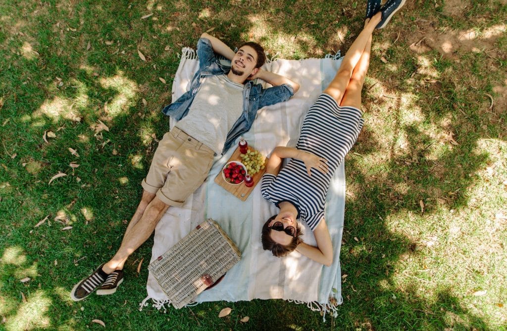 Couple enjoying a relaxing afternoon in the park as a staycation idea.
