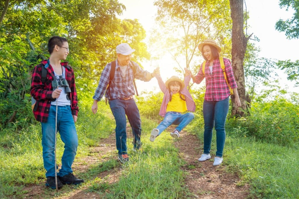 Happy family hiking together in the forest, a perfect example of budget family travel tips focused on free activities.