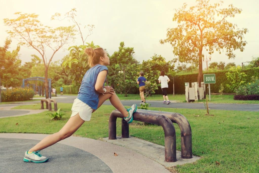 Woman stretching in public park as part of outdoor budget fitness tips