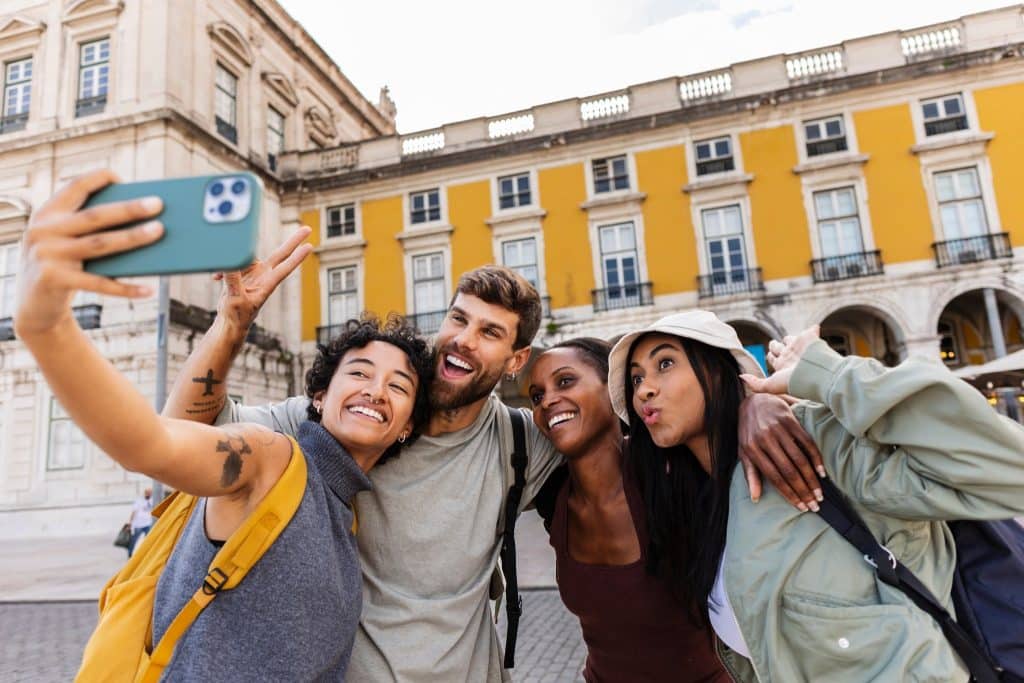 Friends taking a cheerful selfie during budget weekend trips in a historic city square.