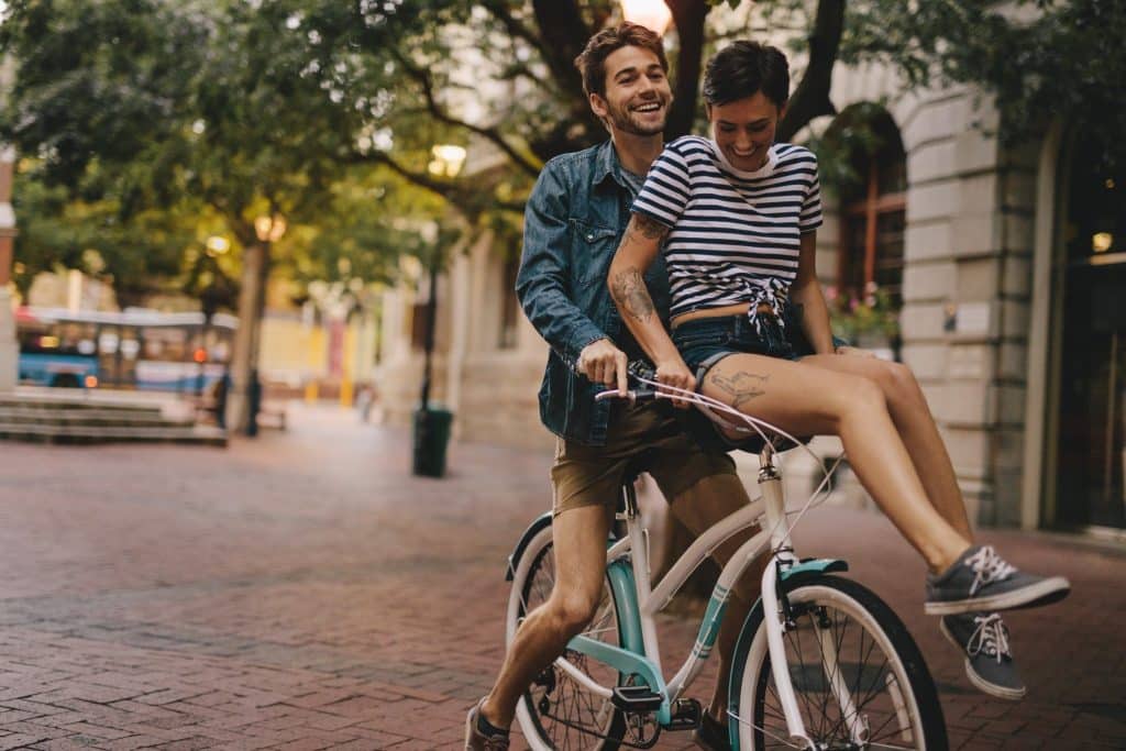 Couple enjoying city exploration on a bike ride as part of their budget weekend trips.