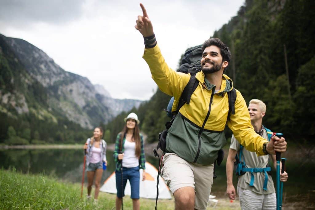 Group of hikers pointing at scenic views while exploring mountains on budget weekend trips.