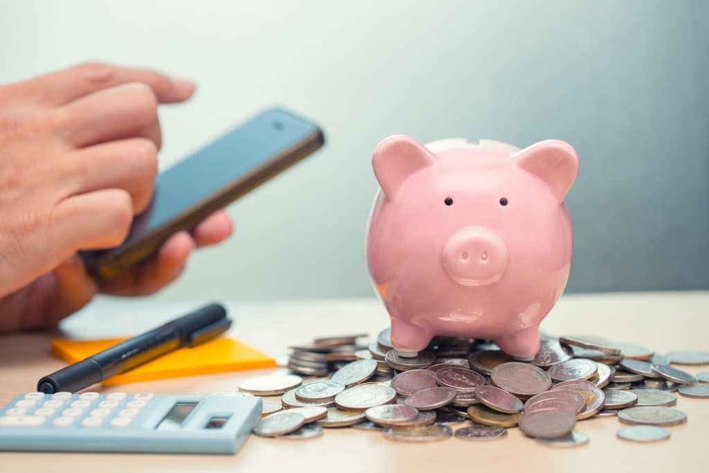 Piggy bank and smartphone with calculator teaching to track every purchase.