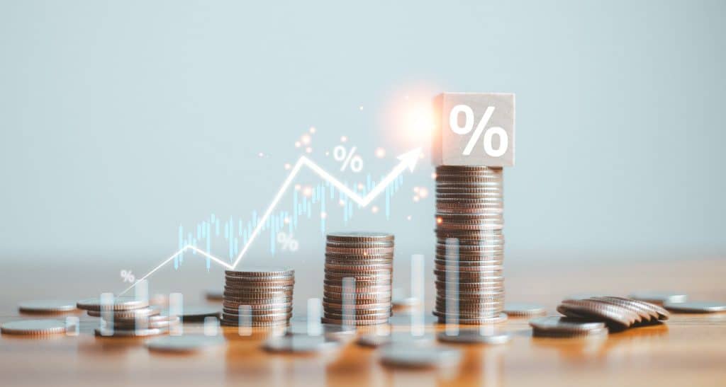 Stacked coins with percentage symbols and growth chart showing small investment strategy for how to retire early.