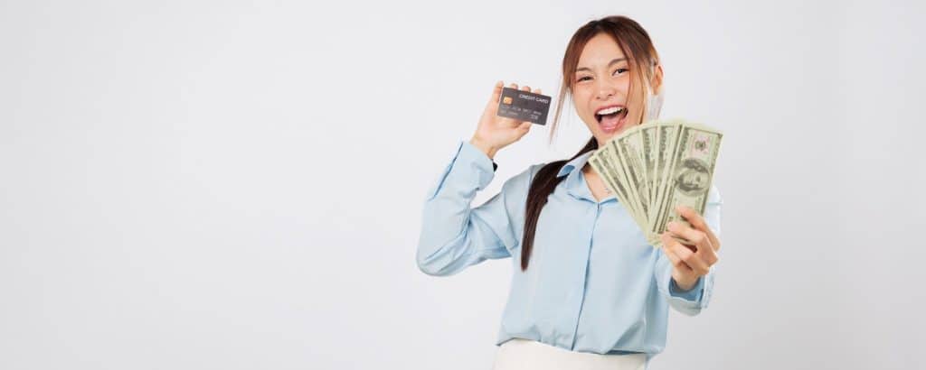 Happy woman with cash and credit card – success in learning how to stop impulse buying.