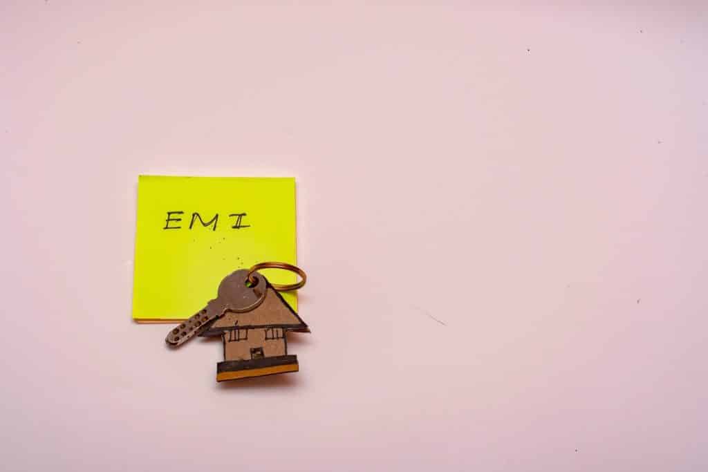 House key and EMI label symbolizing debt and the importance of realistic financial advice for managing home loans.