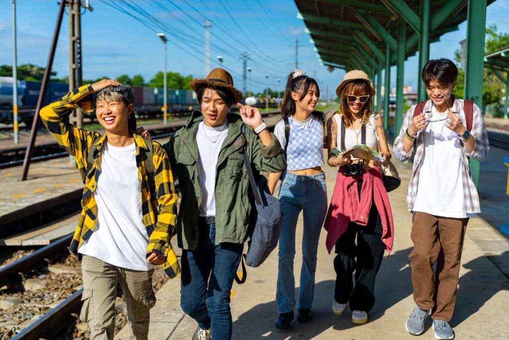 Friends walking at a train station on a group trip travel budget tips for group adventures.