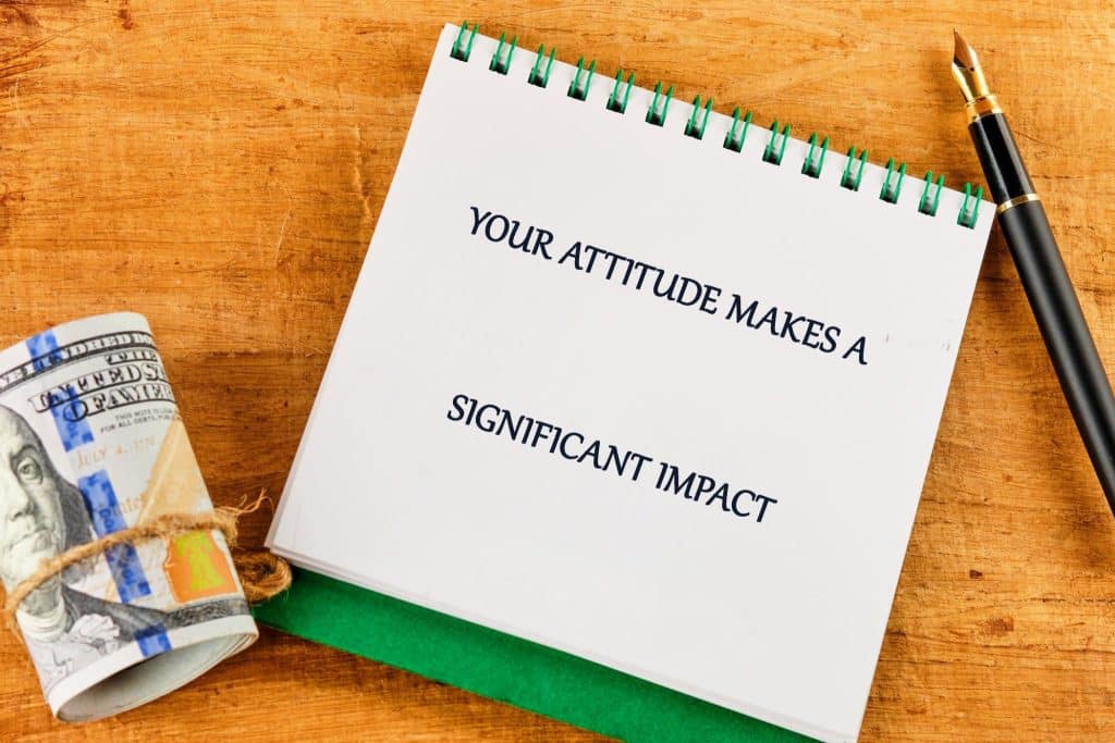 A notebook with the phrase your attitude makes a significant impact shows how mindset supports visualization for financial success.