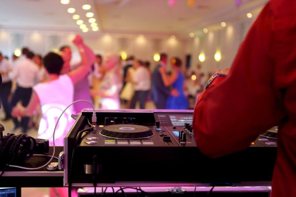 A wedding DJ playing music for guests on the dance floor, showing how wedding budgeting tips can make entertainment fun without overspending.