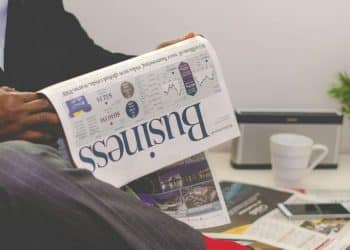 person sitting near table holding newspaper