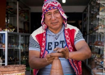 man making clay pot while sitting on chair