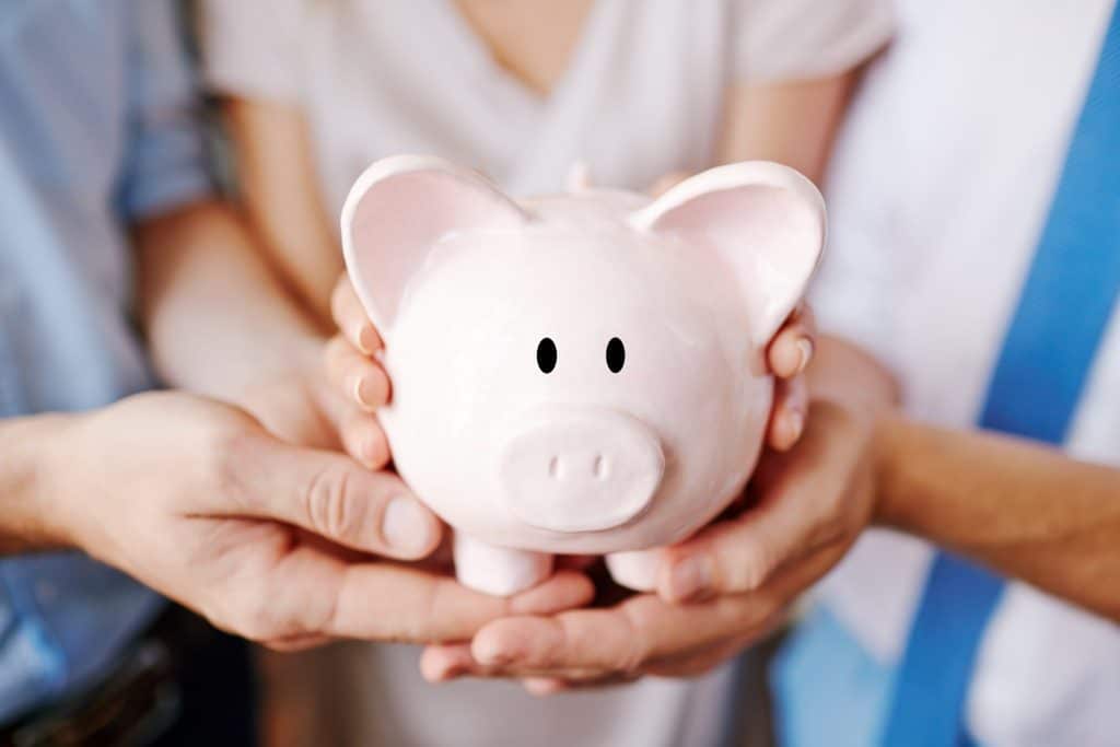 Parents and their kid holding a piggy bank together, symbolizing collective budgeting for a baby and long-term financial planning.