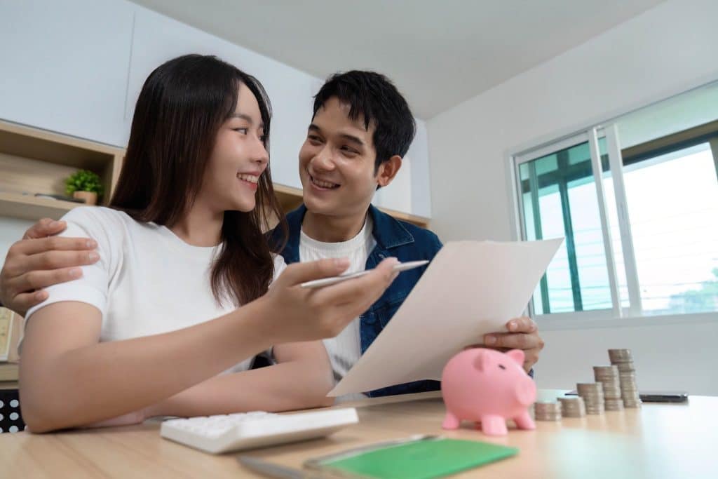 Smiling couple reviewing savings and documents together, promoting the idea of shared financial wellness.