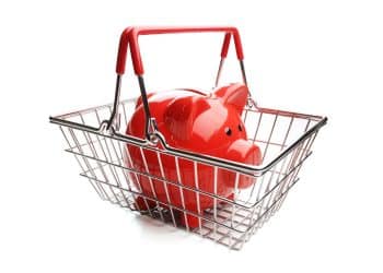 Red piggy bank inside a grocery basket, symbolizing the importance of budgeting to save on groceries.