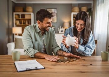 Happy couple counting coins from a piggy bank, showing real-life tips to save money at home.