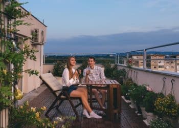 Couple enjoying a sunny picnic in the balcony as part of affordable staycation ideas