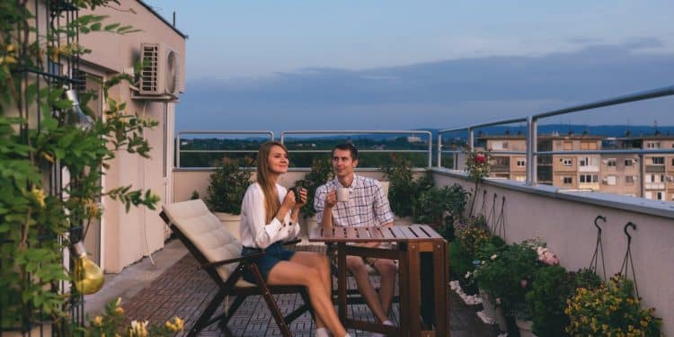 Couple enjoying a sunny picnic in the balcony as part of affordable staycation ideas