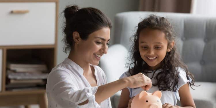 Mother helping her daughter save coins in a piggy bank, a positive step toward breaking bad money habits and learning financial discipline.