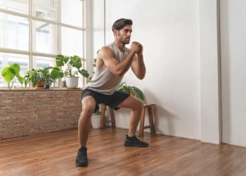 Man doing squats at home as part of budget fitness tips