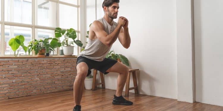 Man doing squats at home as part of budget fitness tips