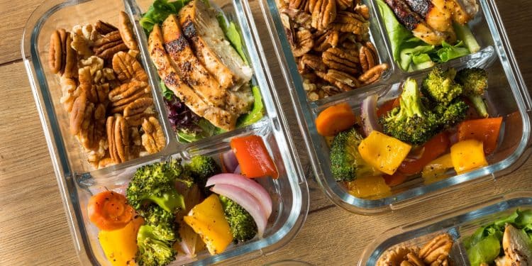 Glass meal-prep containers with chicken, veggies, and nuts—make-ahead lunches for budget meal planning.