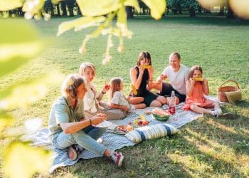 Family sharing food and laughter during a sunny picnic on budget weekend trips.