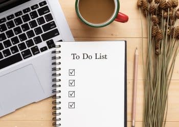 Daily financial habits morning checklist with coffee and laptop.