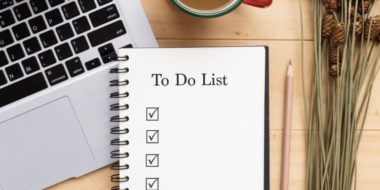 Daily financial habits morning checklist with coffee and laptop.