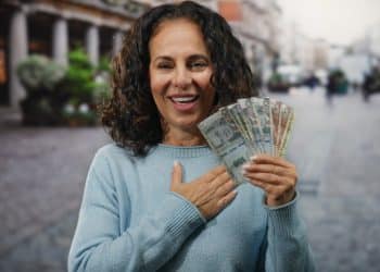 Happy woman holding cash outdoors, symbolizing gratitude and money success.