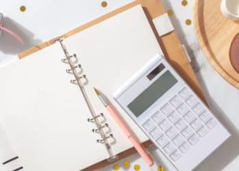 Notebook with calculator, coffee, and holiday decor showing holiday spending tips for financial health and how to save money during those periods.