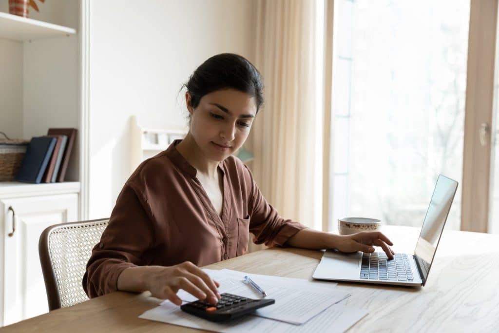 Woman calculating budget to learn how to stop splurging money.
