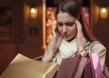 Woman feeling regret after excessive shopping – how to stop impulse buying stress.