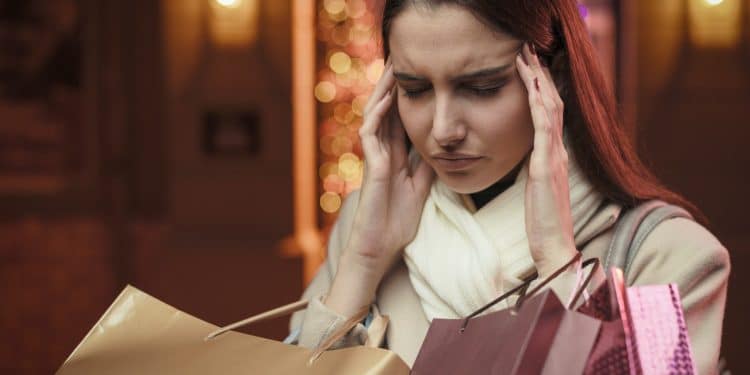 Woman feeling regret after excessive shopping – how to stop impulse buying stress.