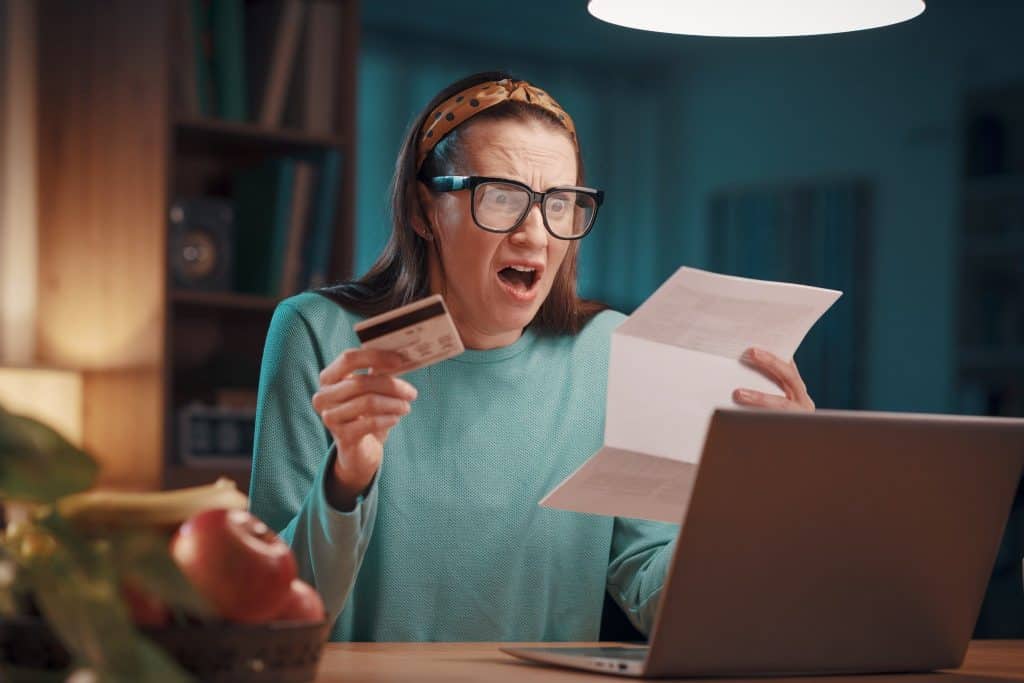 Woman shocked by high credit card interest while managing monthly budget.