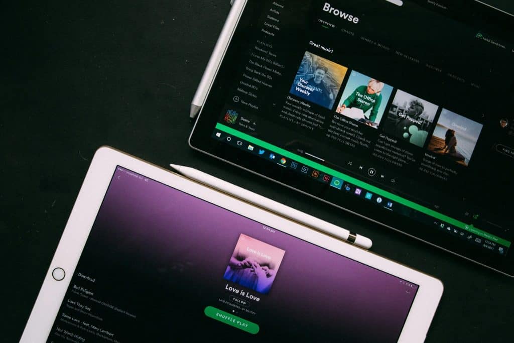 Spotify interface on tablet and phone an example of how to reduce monthly expenses by leveraging streaming services instead of traditional media.