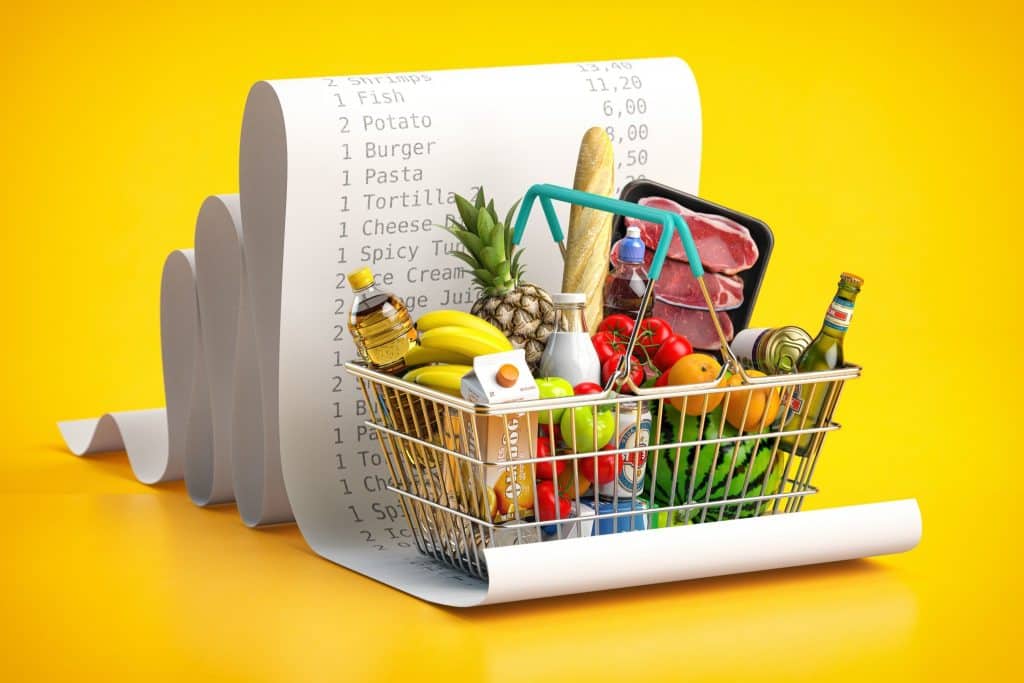 Full grocery basket in front of a long receipt, symbolizing awareness and strategies to save on groceries.