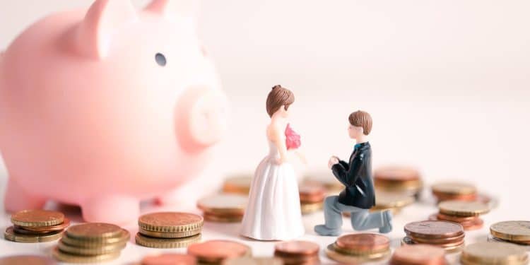 A toy couple planning their wedding expenses with coins and a piggy bank, showing the importance of wedding budgeting tips for a debt free celebration.